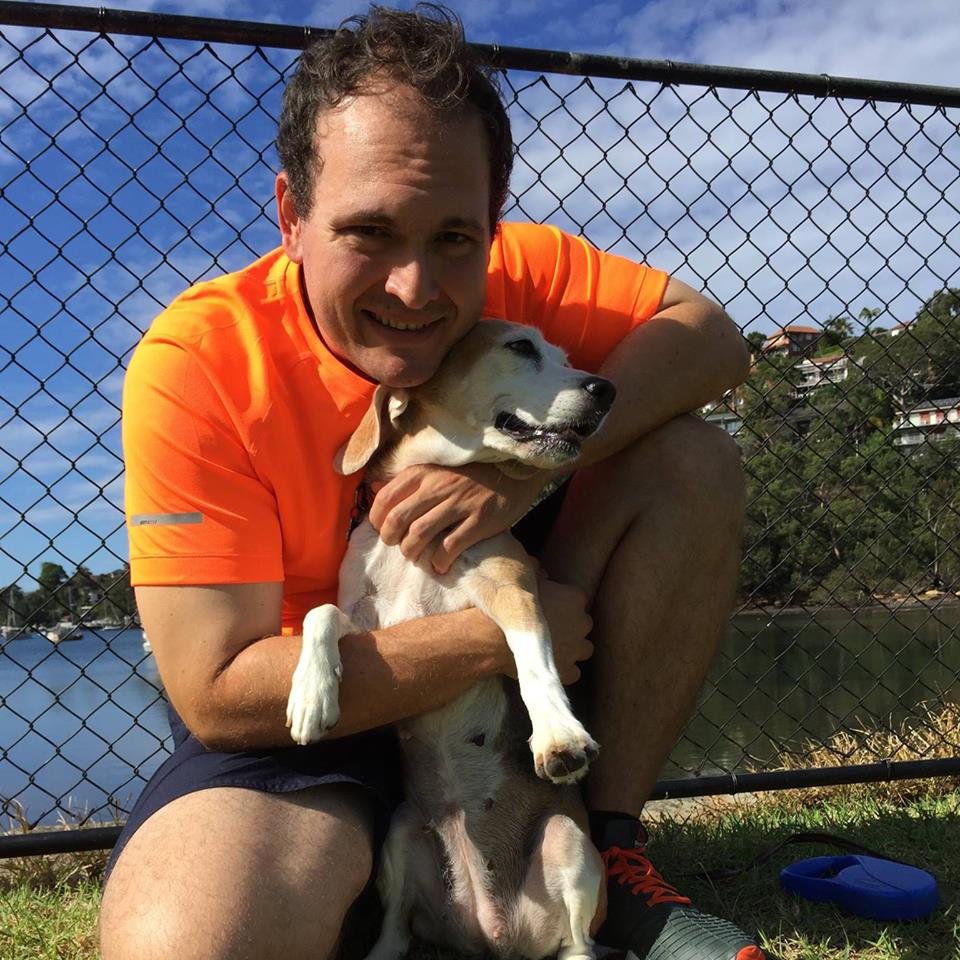 Happy Pups founder hugging his Beagle beside the water